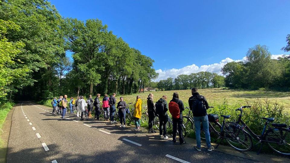 Deelnemers van het leerwerktraject fietsen langs een maisveld in de zon